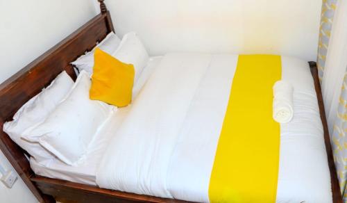 Bett mit weißer Bettwäsche und gelbem Kissen in der Unterkunft Perfection in Meru