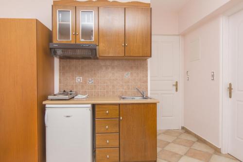 a kitchen with wooden cabinets and a white refrigerator at Welcome Naxos in Agios Prokopios