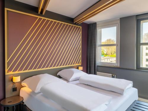 B&B HOTEL Aachen City-Ost في آخن: سريرين في غرفة بها نافذتين