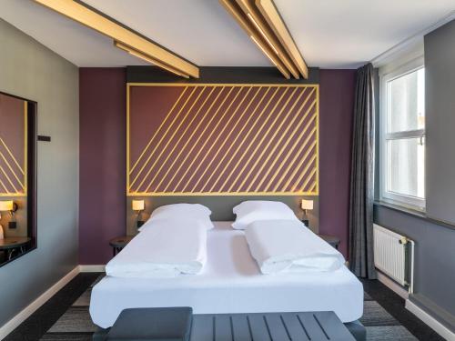 B&B HOTEL Aachen City-Ost في آخن: غرفة في الفندق سرير مع وسائد بيضاء