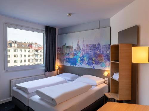 a bedroom with two beds and a large window at B&B HOTEL Aachen City-Ost in Aachen