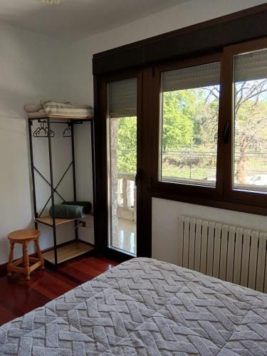 a bedroom with a bed and two windows at Casa Ruliña in Lalín