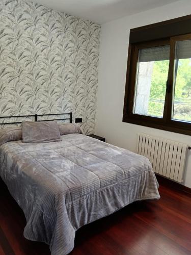 a bedroom with a bed and a window and a wall at Casa Ruliña in Lalín
