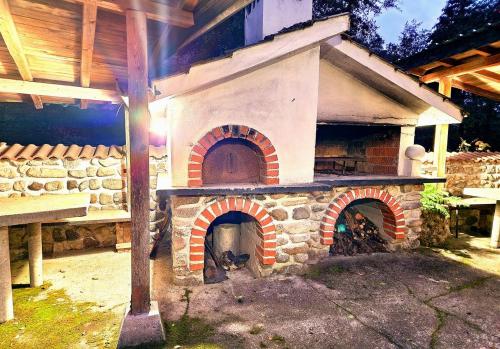 a large brick oven in a yard next to a table at Хотел Механа Воденицата in Zlatkov Chiflik
