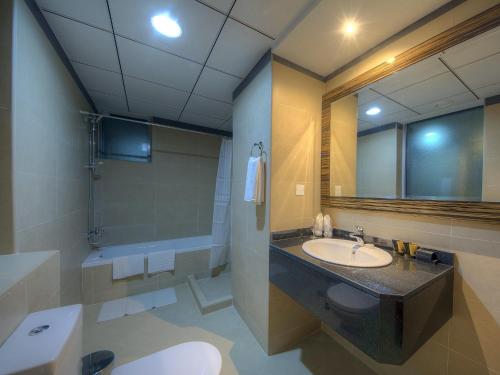 bagno con lavandino, servizi igienici e specchio di Orchid Vue Hotel a Dubai