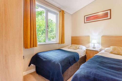 a small bedroom with two beds and a window at Churchill Lodge in Kingham
