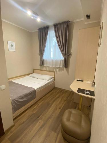 a bedroom with a bed and a desk and a window at Grand Christer Hotel in Kyiv