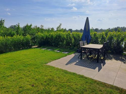 a picnic table and an umbrella next to a field at De Platwever 3B in Zelhem
