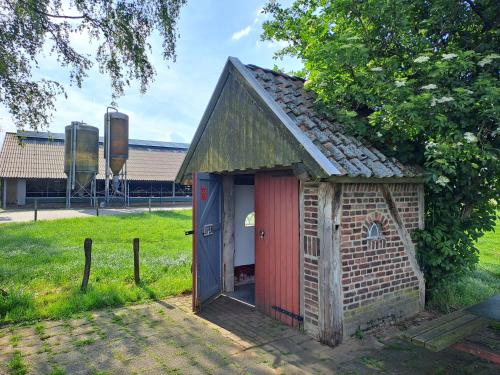 a small brick building with a red door at De Platwever 3B in Zelhem