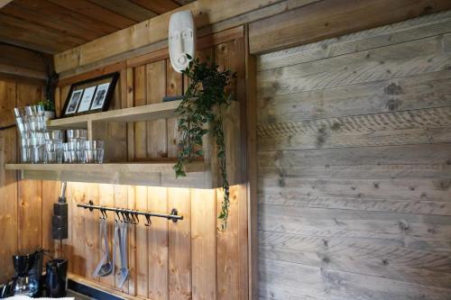 a kitchen with wood paneling and a wall with shelves at Luxe Glamping Met eigen badkamer voor 5 Personen Bashful in Behelp