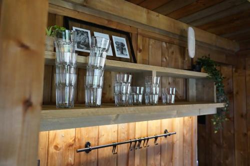 a shelf with glasses sitting on top of a wooden wall at Luxe Glamping Met eigen badkamer voor 5 Personen Bashful in Behelp
