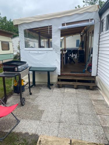 une terrasse avec une table de ping-pong et un grill dans l'établissement Mobil home 3 chambres tout confort, à Sainte-Eulalie-en-Born