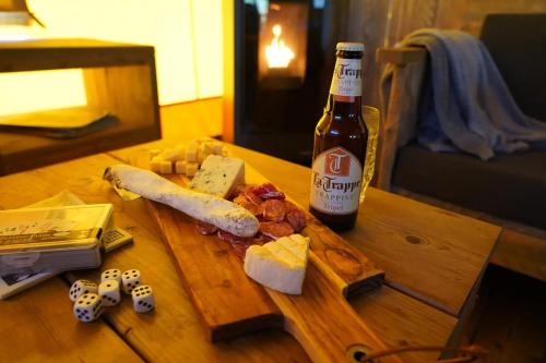 a bottle of beer and cheese on a wooden table at Luxe Glamping Met eigen badkamer voor 5 Personen Bashful in Behelp