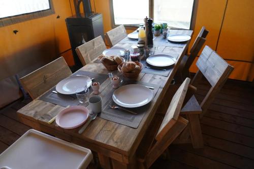 a wooden table with plates and dishes on it at Luxe Glamping Met eigen badkamer voor 5 Personen Bashful in Behelp