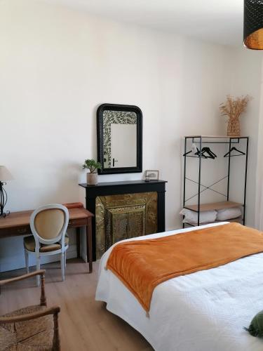 une chambre avec un lit, un bureau et un miroir dans l'établissement Chambres d'hôtes les 2 tilleuls, à Figeac