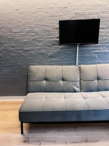a couch in a room with a tv on a brick wall at KonceptHotel in Oksbøl