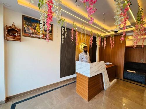 Un homme debout derrière un comptoir dans une pièce fleurie dans l'établissement Goroomgo Hotel Imperial Varanasi - Wonderfull Stay with Family, à Varanasi
