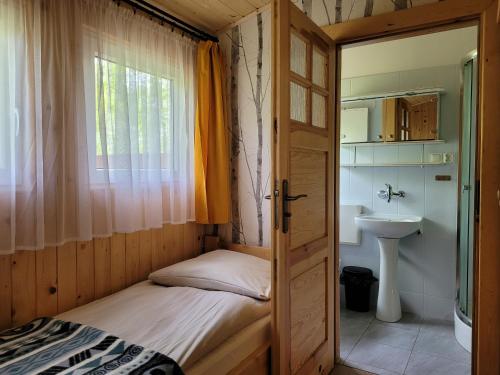 a small bedroom with a bed and a sink at Domki Zacisze, Okoniny in Śliwice
