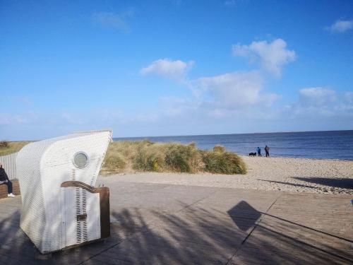 einen weißen Stuhl am Strand in der Nähe des Ozeans in der Unterkunft 48 1 M Seestern in Wangerland