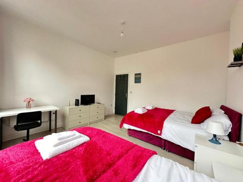1 dormitorio con 2 camas, escritorio y manta roja en Wonderful 2 bed flat in the Bedford town centre, en Bedford