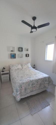 a white bedroom with a bed and a ceiling at Vila Monrealle in Ubatuba