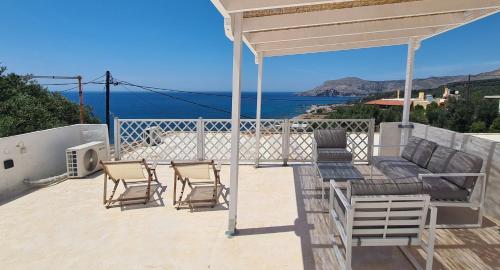 a patio with chairs and a table with a view of the ocean at Colimbos accommodation, 2 min from the beach in Sfinárion