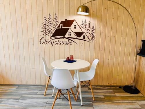 a table with chairs and a house sign on a wall at Obriyslavsko in Slavske