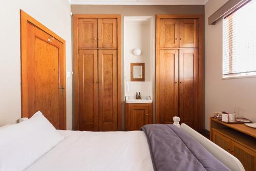 a bedroom with a bed and wooden cabinets and a sink at House Falcon close to ZAH in Pretoria