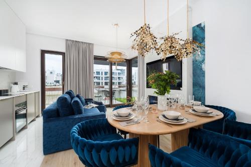 a dining room with a table and blue chairs at Sol Marina Resort Wyspa Sobieszewska II - LoftAffair Collection in Wiślinka