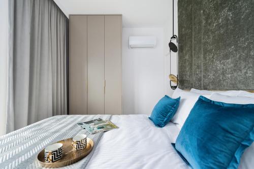 a bed with blue pillows and a tray on it at Sol Marina Resort Wyspa Sobieszewska II - LoftAffair Collection in Wiślinka