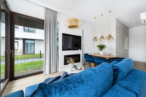 a living room with a blue couch and a table at Sol Marina Resort Wyspa Sobieszewska II - LoftAffair Collection in Wiślinka