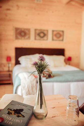 a vase with flowers on a table next to a book at Cabanas de Melides in Melides