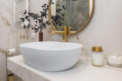 a bathroom with a large white sink and a mirror at Sol Marina Resort Wyspa Sobieszewska II - LoftAffair Collection in Wiślinka