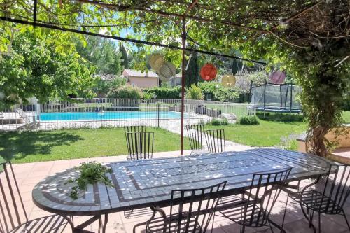 une table de patio avec des chaises et une piscine dans l'établissement Villa piscine Ventoux Provence, à Malaucène
