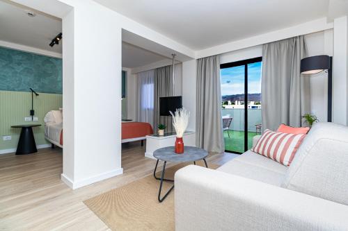 una sala de estar con sofá y una habitación con vistas. en Hotel LIVVO Anamar Suites, en Playa del Inglés