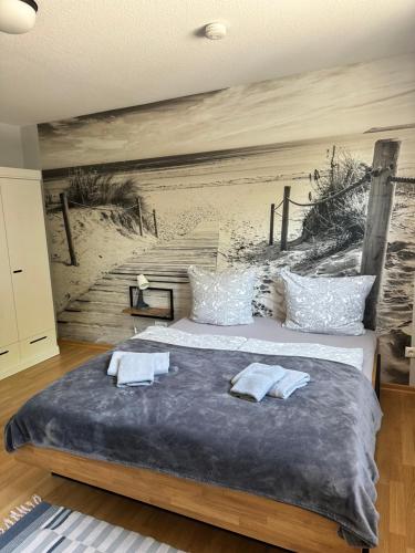 una camera da letto con un letto e un dipinto di una spiaggia di Gasthof Ostwind - ferienwohnungen & meer a Steffenshagen