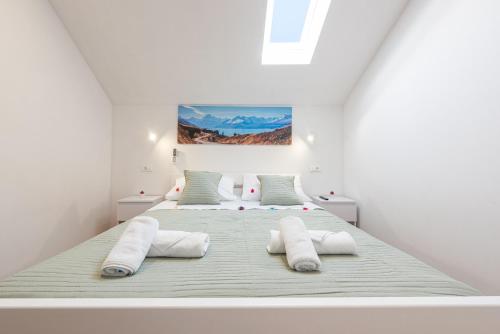 een witte slaapkamer met een groot bed met 2 kussens bij Villa Izvor in Bribir