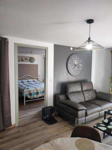 un salon avec un canapé et une horloge au mur dans l'établissement F2 EXTERIEUR LIT KING SIZE, à Brives-Charensac