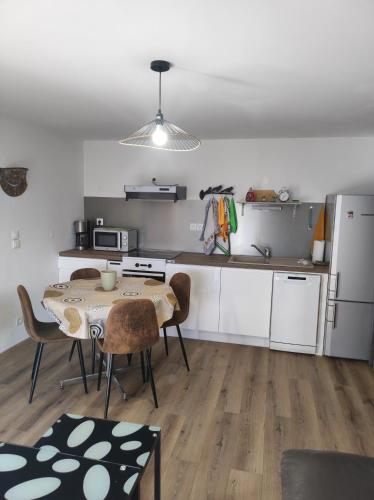 une cuisine avec une table et des chaises dans une pièce dans l'établissement F2 EXTERIEUR LIT KING SIZE, à Brives-Charensac