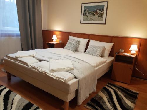 MátraderecskeにあるKét Vándor Fogadóのベッドルーム(白い大型ベッド、ランプ2つ付)