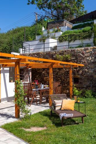 a wooden pergola with a table and a bench at Malomvölgyi Vendégház in Balatonalmádi