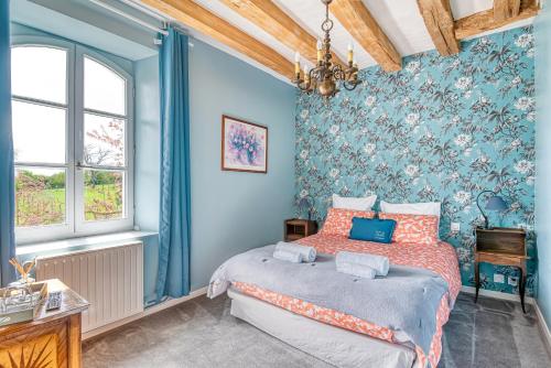 een slaapkamer met blauwe muren en een bed met oranje kussens bij la Fontaine du Mont in Mûrs-Érigné