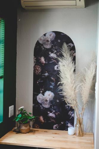 a painting of flowers on a wall with a wooden shelf at The Red door in Rustenburg