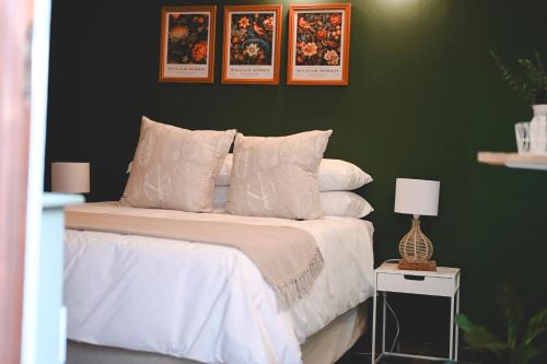 a bedroom with a white bed with a green wall at The Red door in Rustenburg