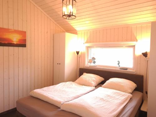 a bedroom with a bed with white sheets and a window at Haus MeerZeit in Sehestedt
