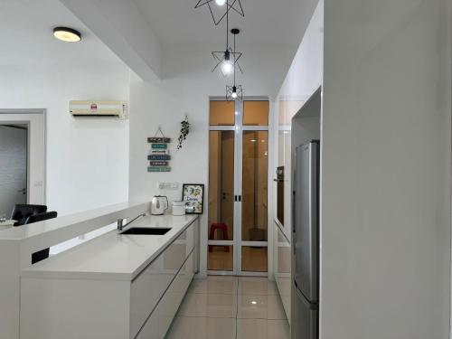 a kitchen with white counters and a refrigerator at Jazz Suites Seaview with Bathtub - 1603 in Tanjong Tokong