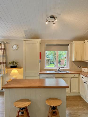 a kitchen with white cabinets and a counter with stools at Norton Plus Lodge 29 in Kingham