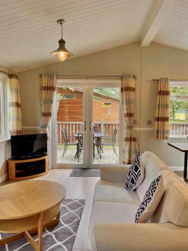 a living room with a couch and a tv and a table at Norton Lodge 29 in Kingham