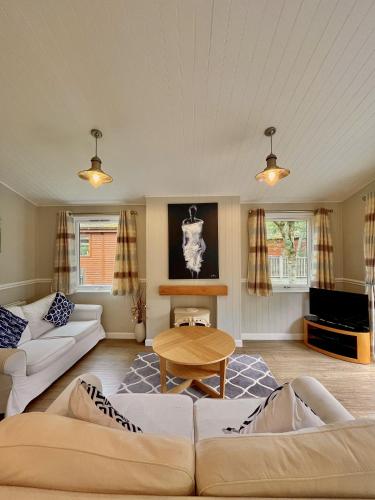 a living room with a couch and a table at Norton Plus Lodge 29 in Kingham