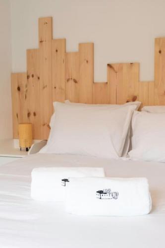 a white bed with white pillows and a wooden headboard at Casa do Pátio do Tejo N12 in Sarilhos Pequenos